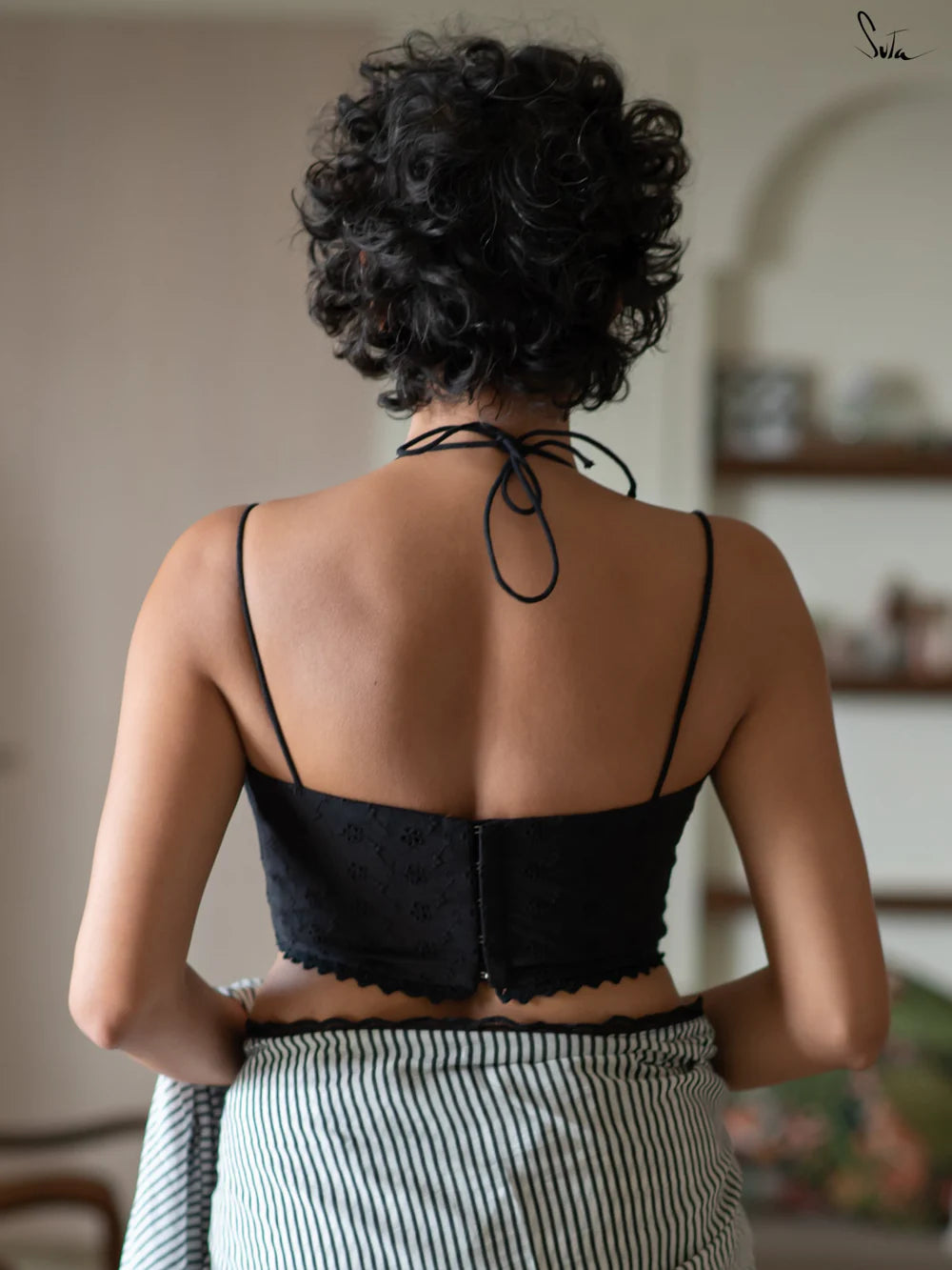 Woman wearing a black halter blouse and saree in an indoor setting