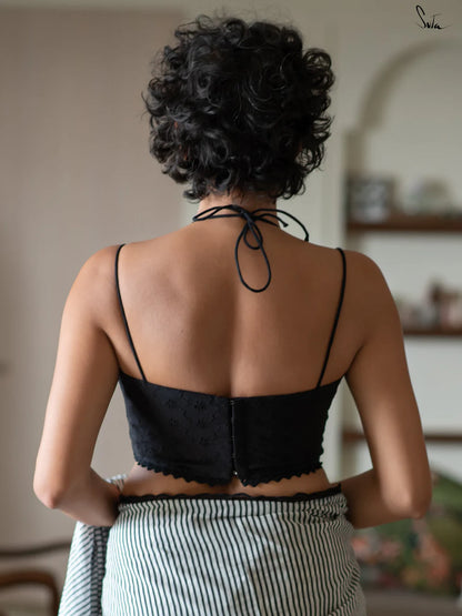 Woman wearing a black halter blouse and saree in an indoor setting