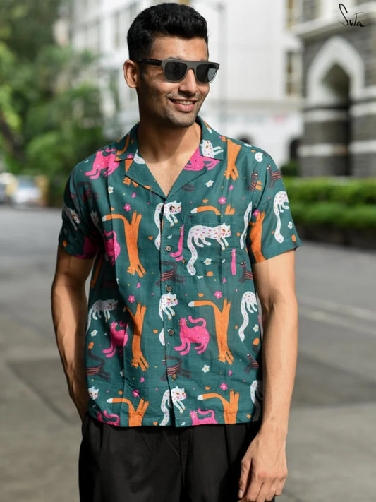 Man wearing a teal colorful patterned shirt on a street background