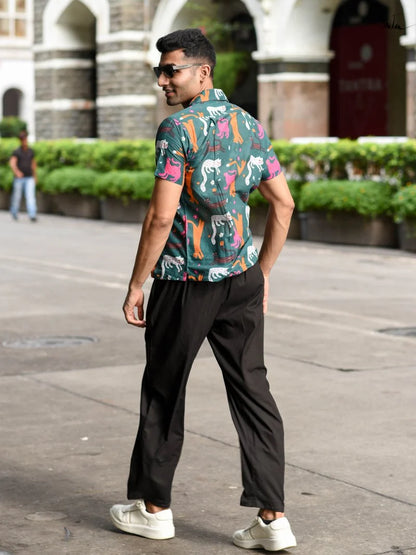 Man wearing a colorful patterned shirt and black pants walking on a street.
