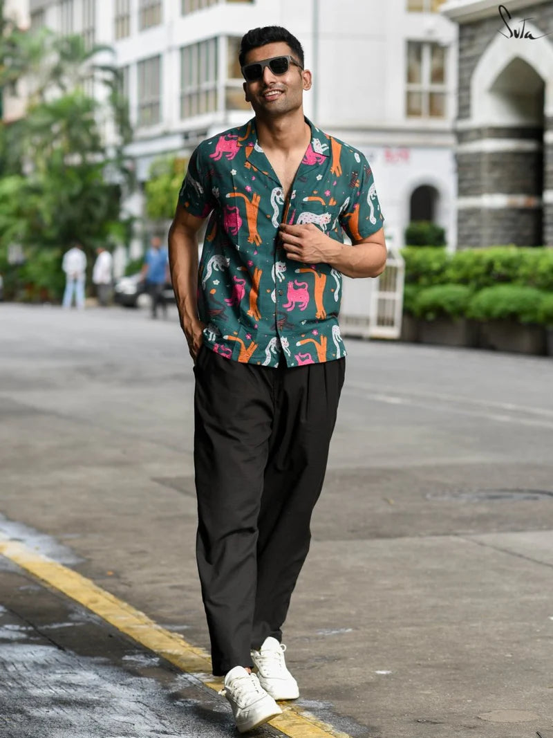 Man walking on a street wearing a colorful shirt and sunglasses