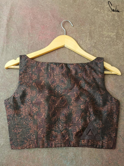 Brown patterned blouse on a hanger against a textured gray background