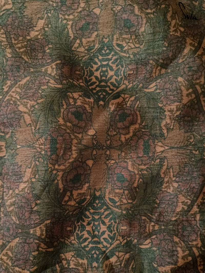 Close-up of a textured fabric with intricate patterns in green, brown, and beige.