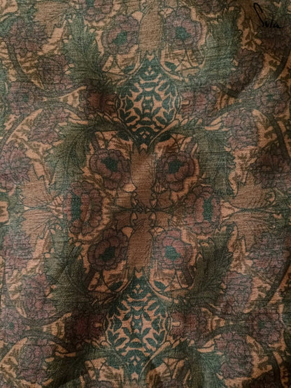 Close-up of a textured fabric with intricate patterns in green, brown, and beige.