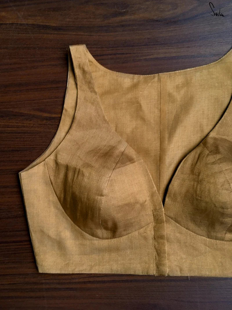 Gold sleeveless blousee on a wooden surface