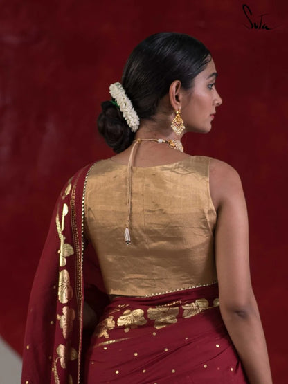Woman wearing a traditional red saree with gold details, gold blouse against a red background