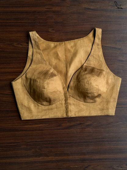 Gold sleeveless blouse on a wooden surface