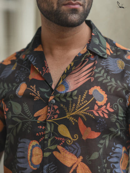 Man wearing a dark floral patterned shirt with a blurred background