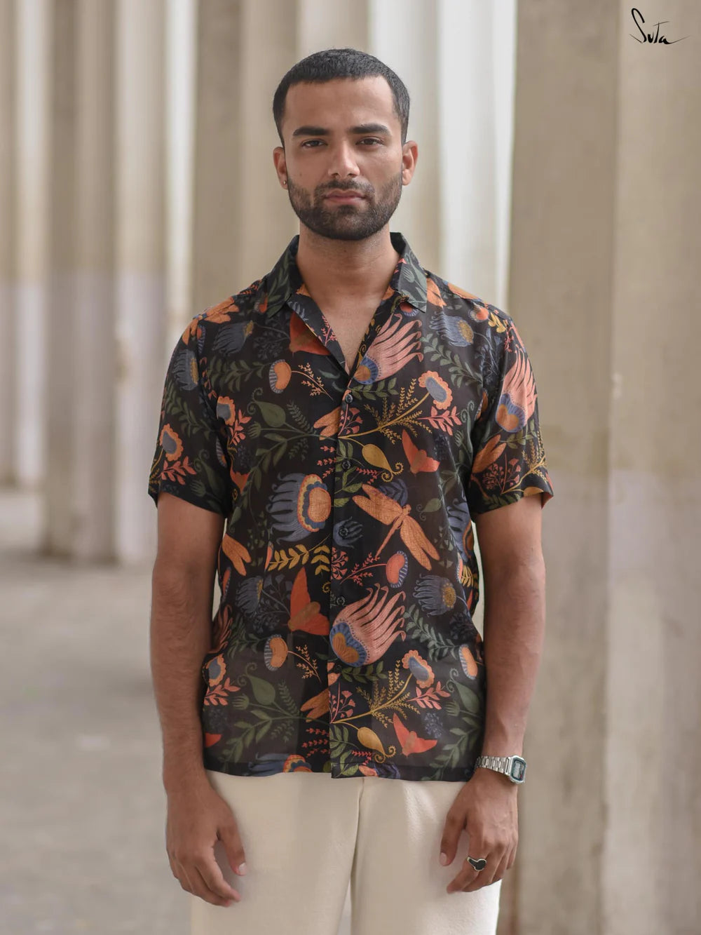 Man wearing a patterned shirt standing in front of classical architecture