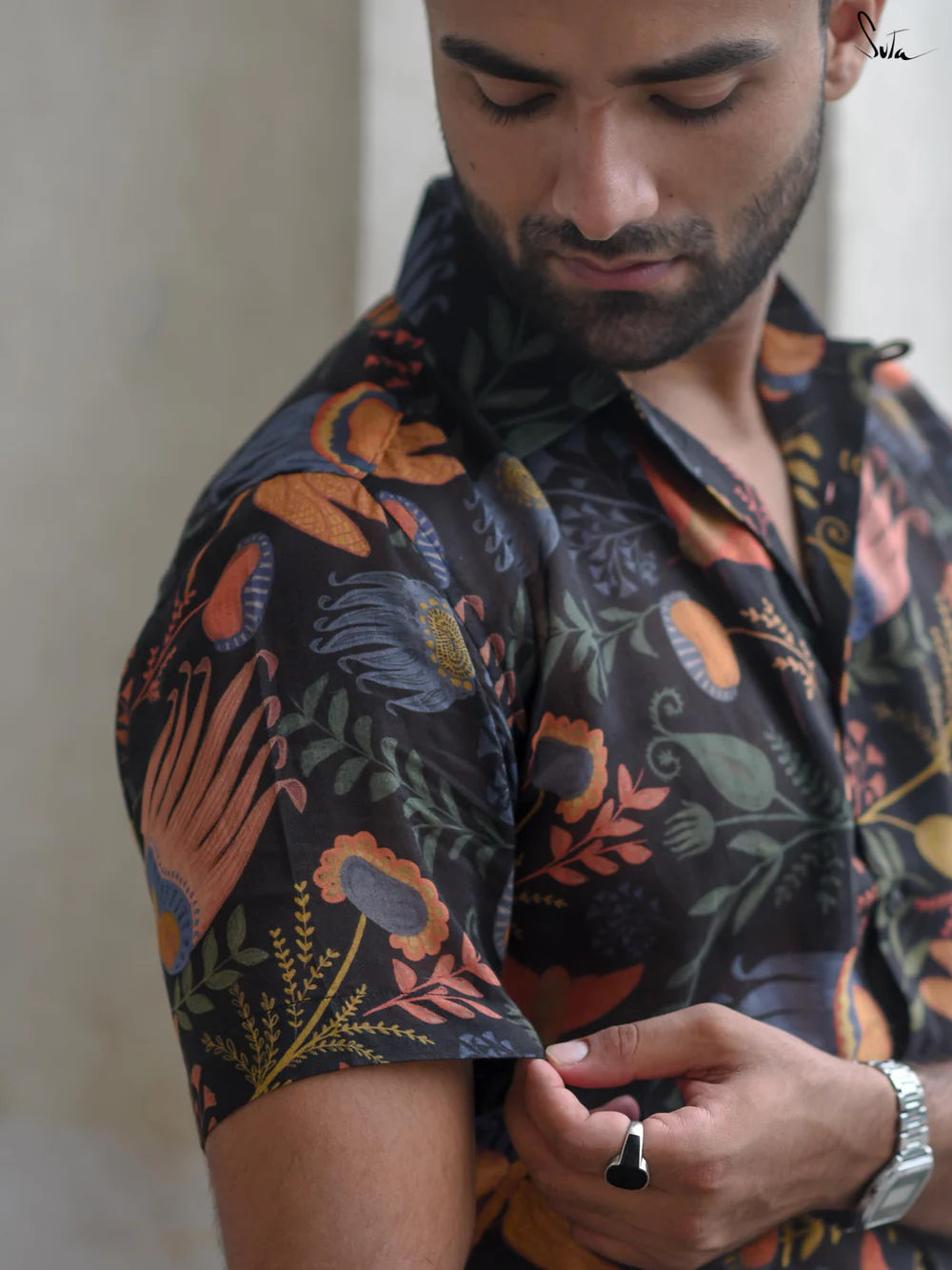 Man wearing a patterned shirt with a neutral background